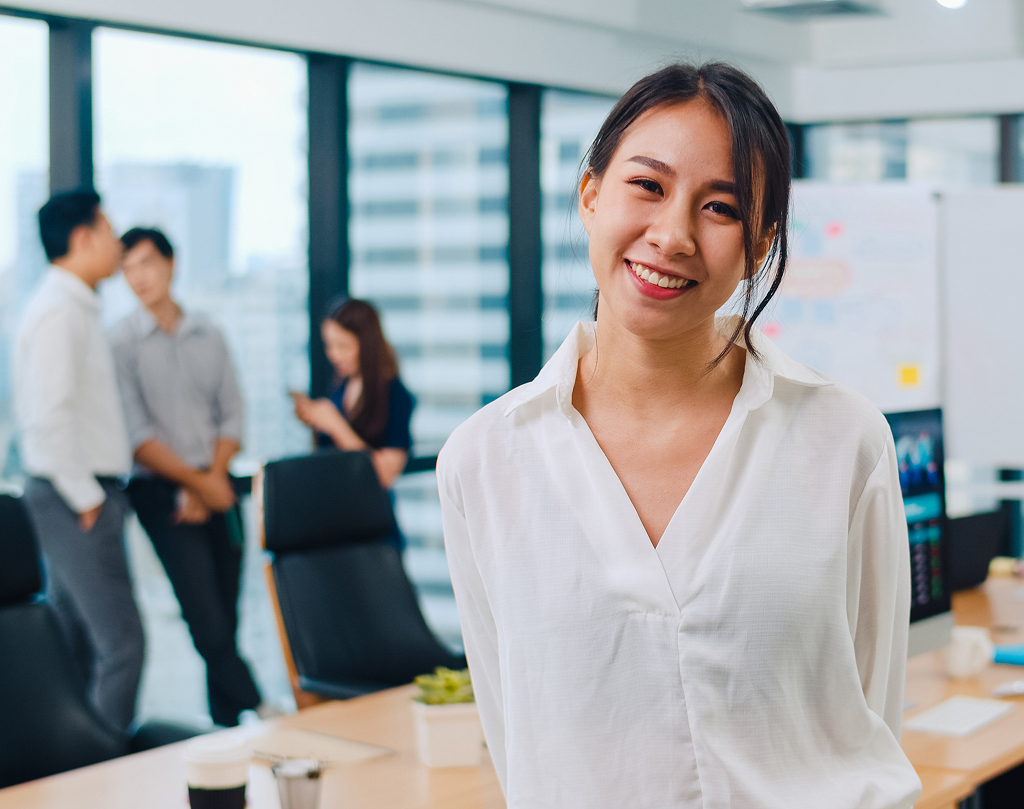 Successful Asian executive businesswoman in smart casual wear smiling in a modern office
