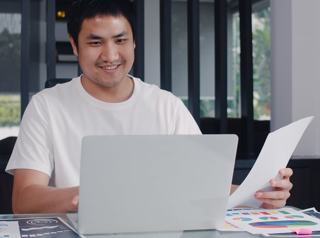 Young Asian businessman recording income and expenses on a laptop — offshore accounting role