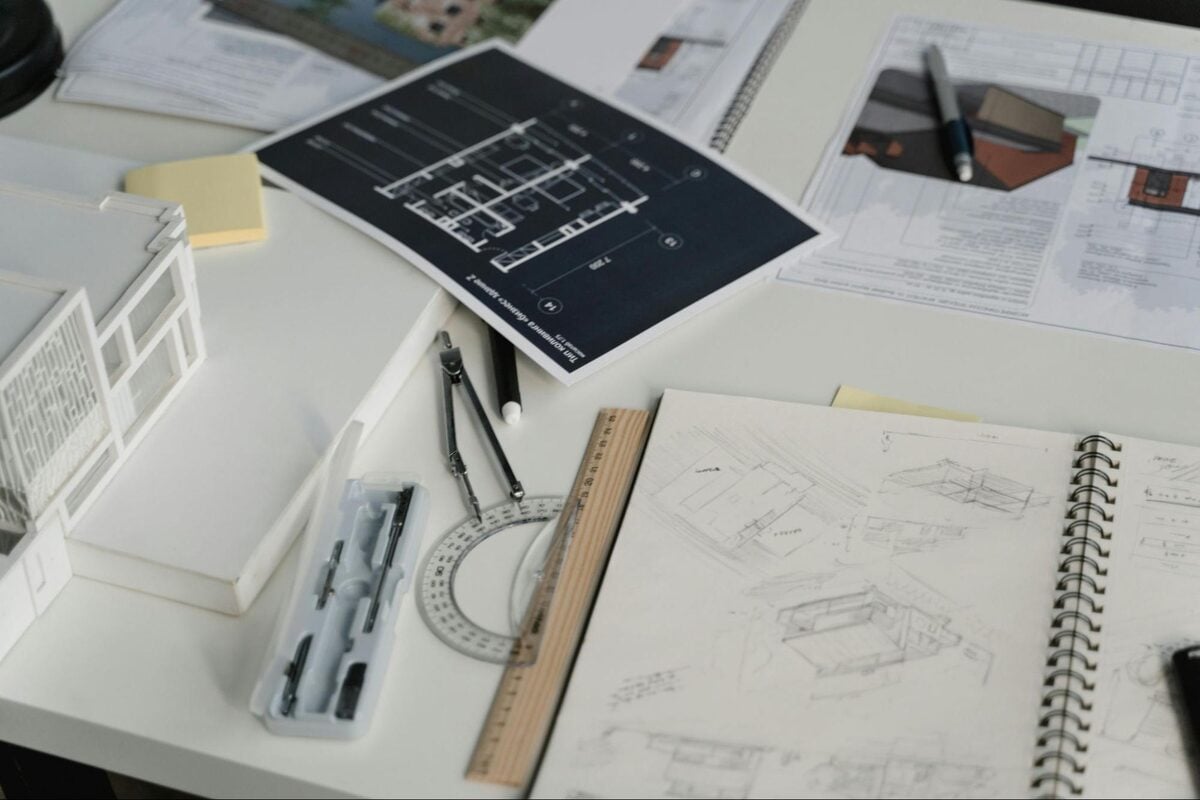 Architectural floor plans, hand sketches and drafting tools on a designer's desk