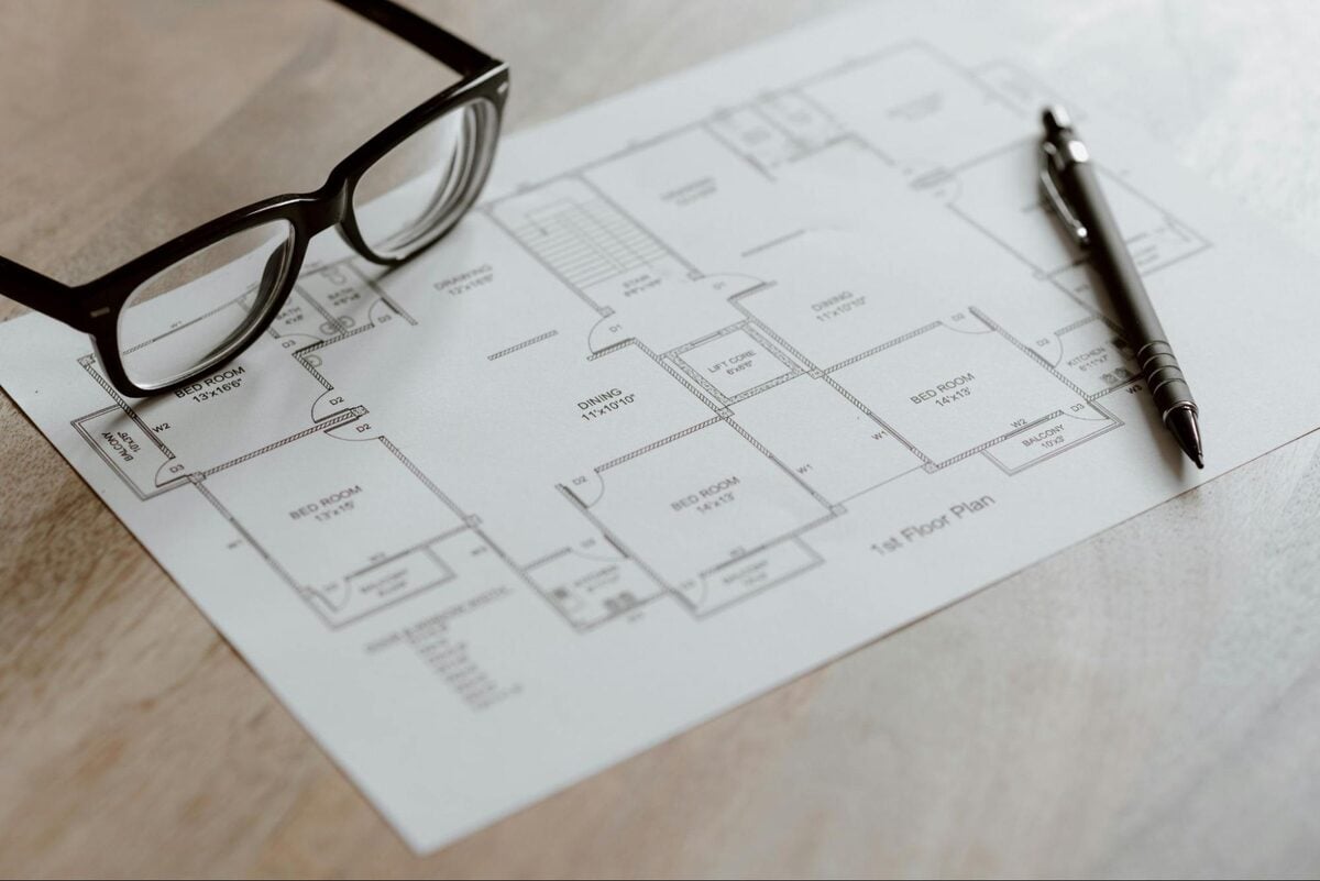 Reading glasses and a pen resting on a printed architectural floor plan