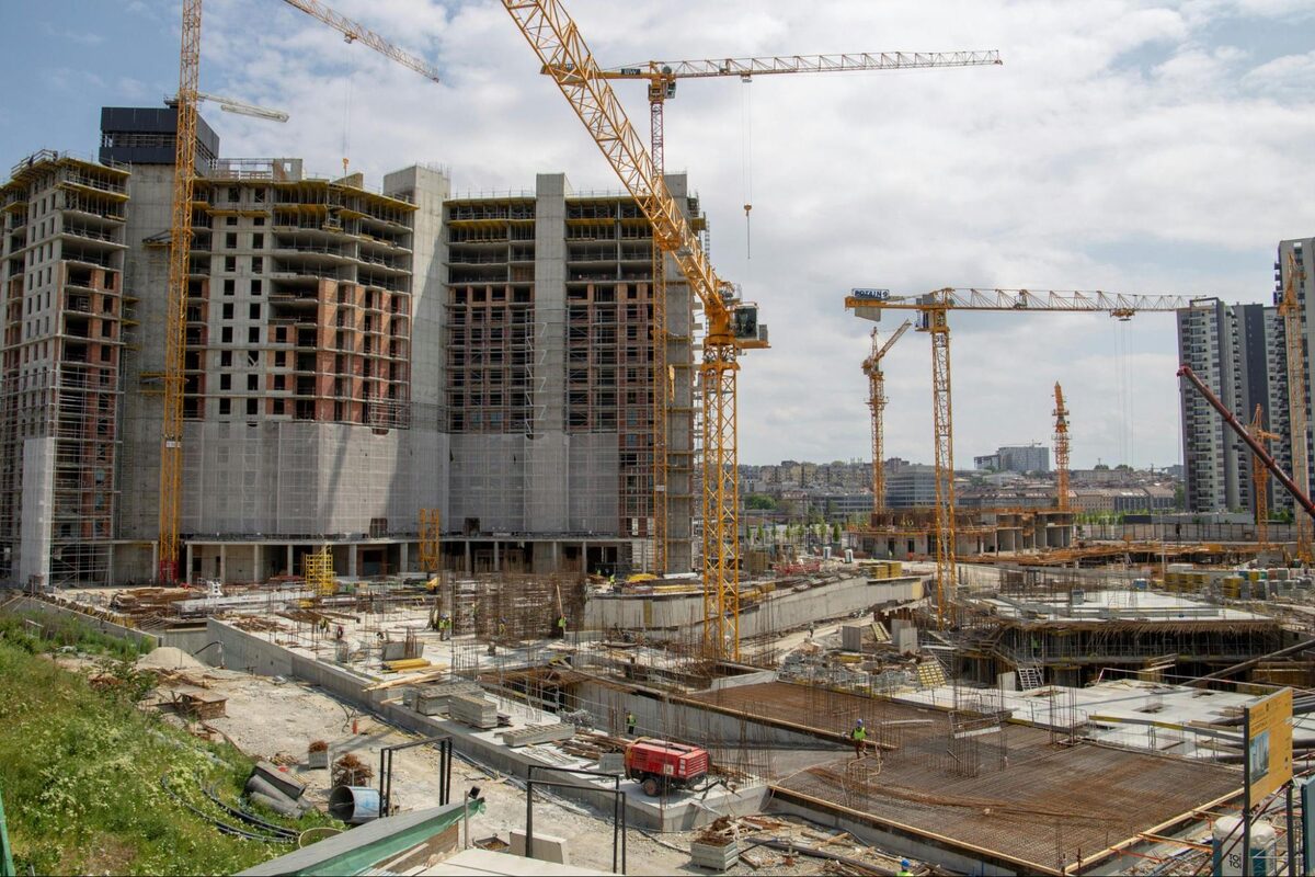 Large multi-tower construction site with several tower cranes at work