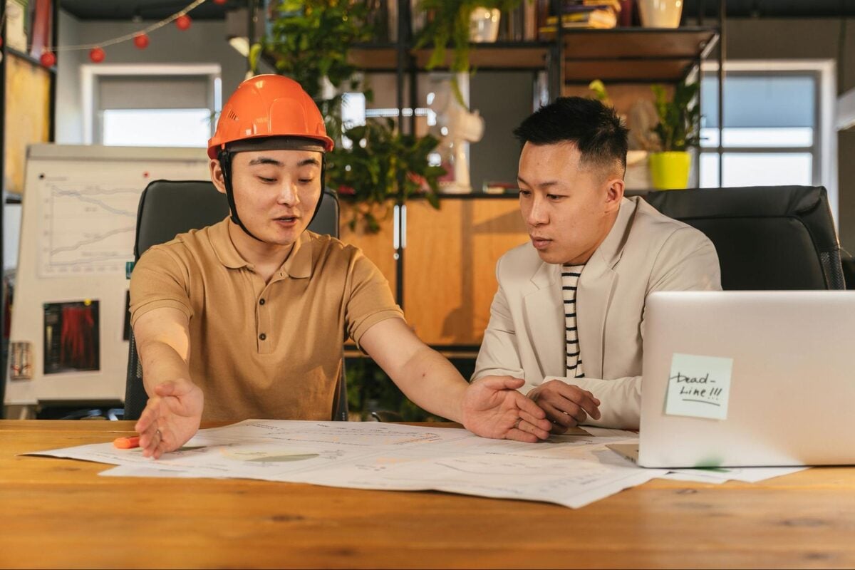Construction professional and manager discussing project plans at a desk