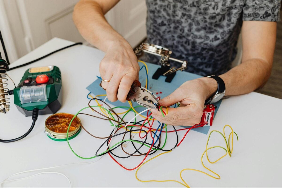 Electrical engineer stripping and connecting coloured wires at a workbench