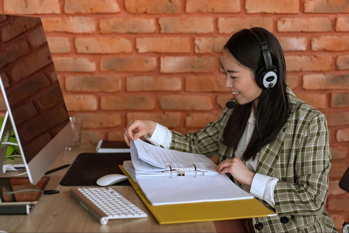 Offshore project coordinator wearing a headset reviewing project documents at her desk