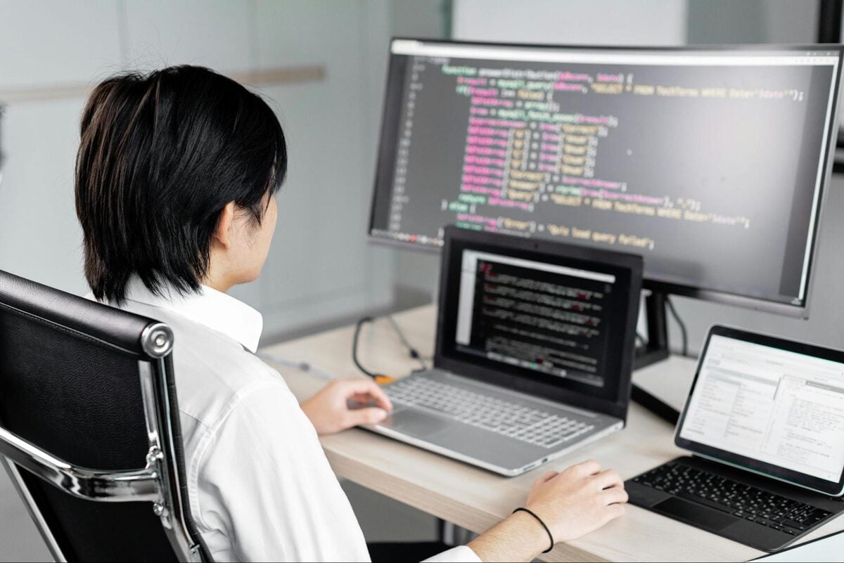 Offshore software developer writing code on a monitor and laptop