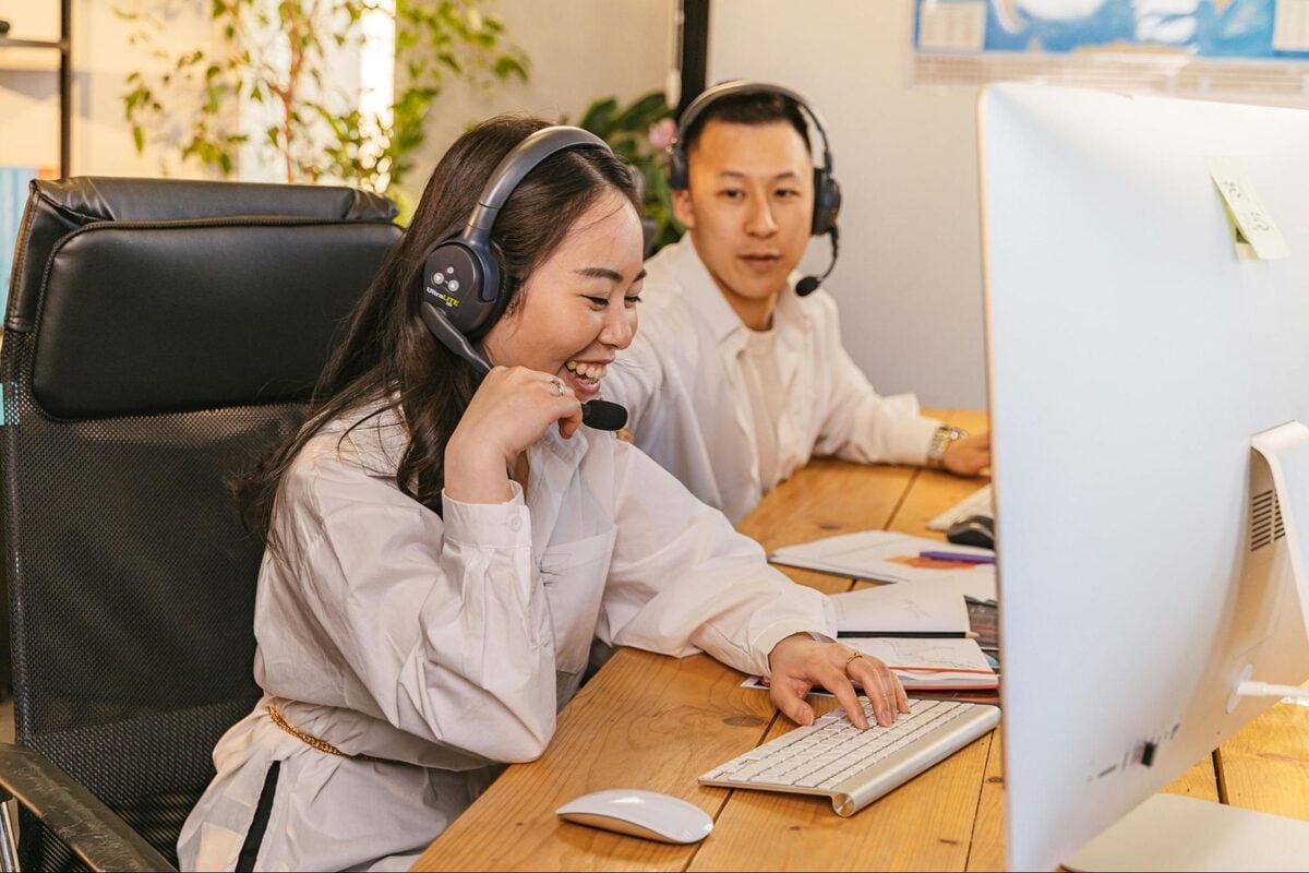 Offshore support team members wearing headsets working together at a computer