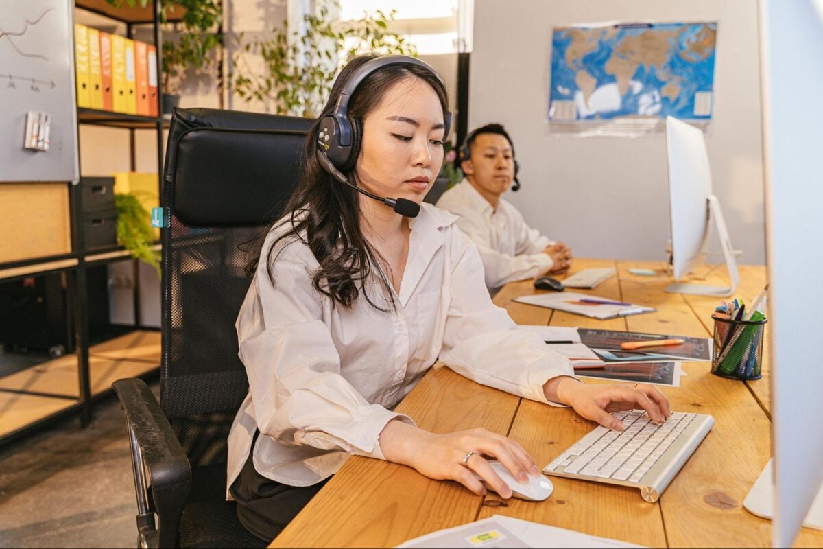 Offshore team members working at computers with headsets in an office